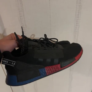 Adidas Nmd v2  - Snygga svarta Adidas sneakers med röda och blå detaljer. Knappast använda (5-10 gånger max), nytt skick och väl bevarade. Pris kan diskuteras!