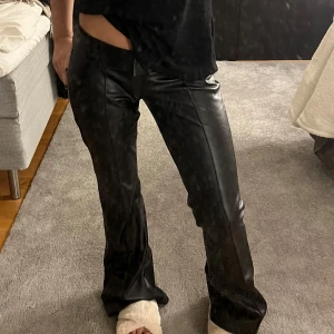 Svarta skinnbyxor - Snygga svarta skinnbyxor med låg midja och bootcut-stil. Lite långa på mig.