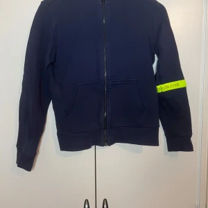 Mörkblå mjukisbyxor från Calvin Klein Jeans - Snyggt set från Calvin Klein Jeans med neongula detaljer längs sidorna. Perfekta för en avslappnad stil med en bekväm passform. Byxorna har elastisk midja och fickor baktill.