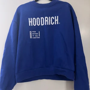 Blå sweatshirt från Hoodrich - Snygg blå sweatshirt från Hoodrich med tryck både fram och bak. Texten 'FROM NOTHING TO SOMETHING' och 'WELCOME TO THE FAMILY' ger en cool streetwear-känsla. Perfekt för en avslappnad stil.