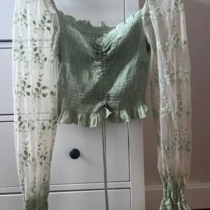Grön blus med spetsdetaljer - Jättefin grön blus med långa, ärmar med blommig spets. Jättefint skick, använt 2-3 gånger.