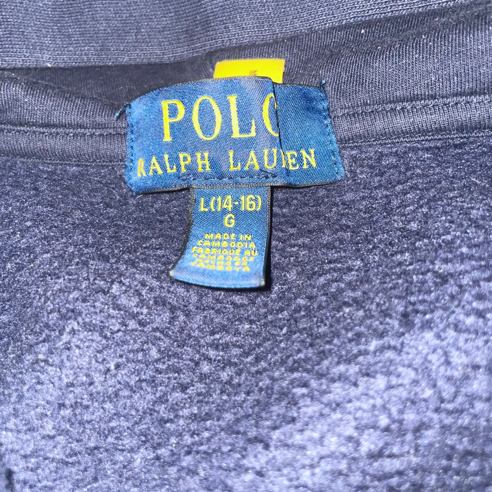 Säljer en snygg mörkblå hoodie från Ralph Lauren med dragkedja och röd logga på bröstet. Tillverkad i en mjuk bomullsblandning med fickor framtill. Perfekt för en avslappnad stil.. Hoodies.