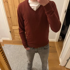 Vinröd tröja från Hansen & Jacob - Säljer en snygg vinröd tröja från Hansen & Jacob i storlek S men passar XS. Den är gjord av ren merinoull vilket gör den supermjuk och perfekt för kyliga dagar. Tröjan har en v-ringad design och långa ärmar, vilket ger en klassisk look. Perfekt för både vardag och lite finare tillfällen. Skriv om ni har några frågor eller funderingar!