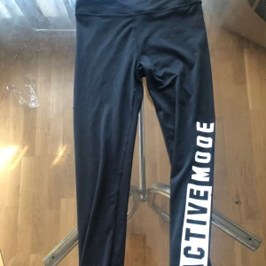 Ett par träningstights - Ett par svarta träningstights men text på högre nedre ben