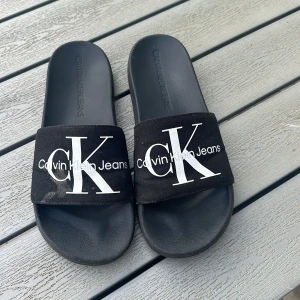 Calvin Klein tofflor  - Ett par tofflor.