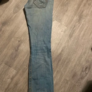 Lågmidjade true religion jeans - Lågmidjade bootcut jeans från true religion. Säljer eftersom de är för stora. Är i bra skick utöver hålen längst ner i benen 84cm i innerbenslängd 