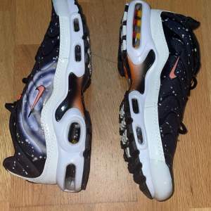 Säljer ett par riktigt coola Nike Air Max med ett unikt galaxmönster. Skorna har en svart bas med vita stänk som ger en rymdliknande effekt. De har en synlig Air Max-dämpning i sulan och en orange swoosh-logga på sidan. Perfekta för dig som vill sticka ut!