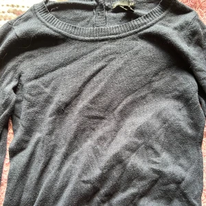 Svart stickad tröja med knappar - Säljer en stilren marinblå  stickad tröja med knappar på ryggen. Tröjan har en rund halsringning och långa ärmar, perfekt för kyligare dagar. Den är både bekväm och snygg, passar till det mesta i garderoben!