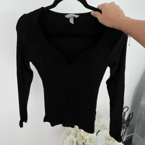 Svart långärmad tröja - En ribbat svart långärmad tröja från H&M med en fin hjärtformad urringning. Dubbelt tyg vid brösten, så ingen bh behövs! Tight i modellen, sitter fint på mig som har S 💞🙌🏻 Mycket stretch!  Använd max 3 gånger 💘  Längd: 52 cm Axel: 32 cm