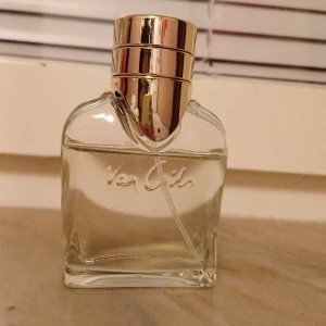 Van Gils parfyn - Säljer en elegant parfym från Van Cleef & Arpels. Flaskan är genomskinlig med en lyxig guldig kork. Perfekt för den som vill ha en sofistikerad doft på hyllan. Flaskan har en stilren design med märkets namn ingraverat på framsidan.