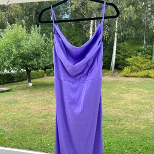 Lila klänning i satin - En lila klänning i satin. Säljer den pga att den aldrig blev använd 💜 Slits längs med vänster ben och dragkedja i ryggen. Passar bra till mig som har storlek S. Justerbara axelband 🥰🌷  (ALDRIG ANVÄND)  Längd: 127 cm Midja: 73 cm Byst: 86 cm
