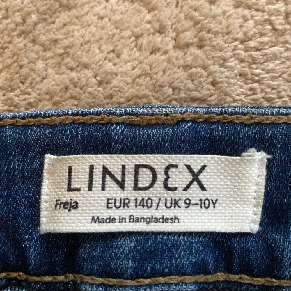 Säljer ett par snygga blå bootcut jeans från Lindex i storlek EUR 140, vilket passar för barn i åldern 9-10 år. Jeansen har en klassisk femficksdesign och är tillverkade i ett slitstarkt denimtyg. Perfekta för både vardag och festliga tillfällen!. Jeans & Byxor.