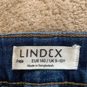 Blå bootcut jeans från Lindex - Säljer ett par snygga blå bootcut jeans från Lindex i storlek EUR 140, vilket passar för barn i åldern 9-10 år. Jeansen har en klassisk femficksdesign och är tillverkade i ett slitstarkt denimtyg. Perfekta för både vardag och festliga tillfällen!