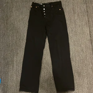 Svarta Levis Premium jeans - Säljer ett par snygga svarta Levis Premium jeans i modellen 'Ribcage Straight'. De har en hög midja och raka ben, vilket ger en klassisk och stilren look. 