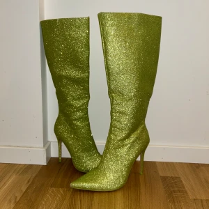 Glittriga gröna stövlar från Public Desire - Snygga och iögonfallande gröna stövlar med glittrig yta från Public Desire. Skorna är som nya då jag bara haft på mig dom en gång, storlek 38 men passar även 39 då dom är lite stora i storleken 