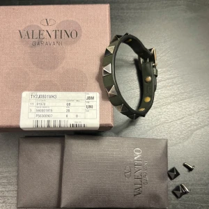 Valentino armband  - Snyggt svart armband från Valentino med coola pyramidformade nitar i silver. Armbandet är justerbart och har en stilren design som passar perfekt för både vardag och fest. Kommer i originalförpackning.