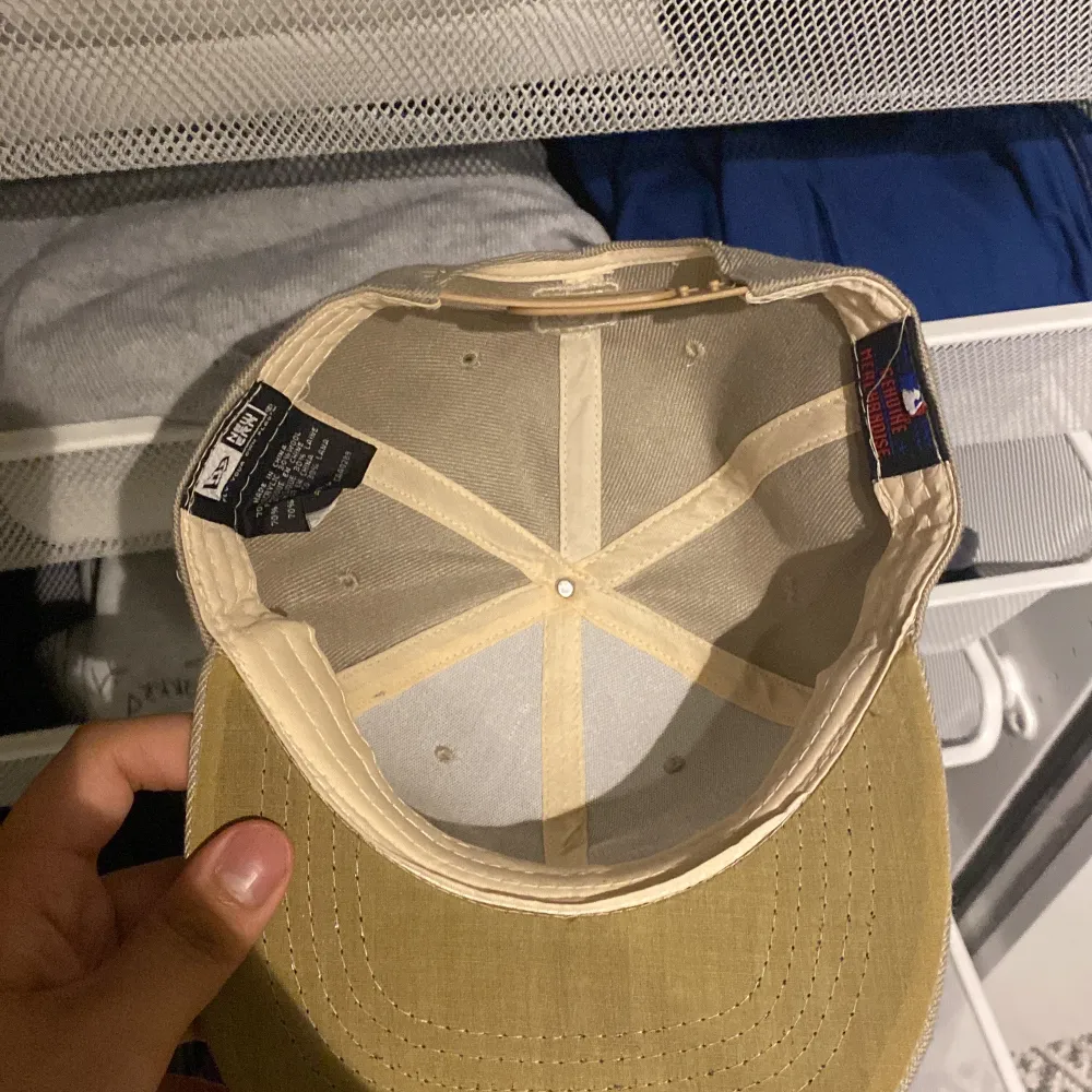 Säljer en beige snapback-keps från New Era med 'A's' broderat framtill. Kepsen har en justerbar rem baktill och MLB-logga. Perfekt för sommardagar eller som en stilren accessoar.. Asusteet.