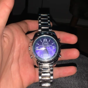 Silverfärgad klocka med blå urtavla - Säljer en snygg klocka i silver med en cool blå urtavla. Den har en robust metallarmband och flera små urtavlor för extra funktioner. Perfekt för både vardag och fest! 🕒✨