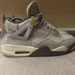 Jordan 4 carft  - Säljer ett par grå Nike Air Jordans carft  i mycket bra skick. Skorna har en snygg kombination av mocka och syntetmaterial med klassisk snörning. De har en stilren design med ljusgrå och beige detaljer, perfekt för både vardag och fest. Storlek herr 43