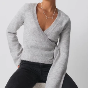 Grå omlottkofta från Gina Tricot - Säljer en superfin grå omlottkofta från Gina Tricot i storlek XS. Den är stickad och har långa ärmar med en snygg knytning i sidan. Perfekt för höst och vinter när du vill vara både stilren och varm. Den är helt ny utan prislapp, aldrig använd. Koftan säljs på fler sidor därav går det inte att trycka på köp nu, men skriv om du vill köpa så löser jag det🩶