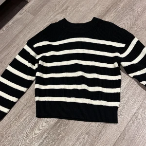 Svart och vit randig stickad tröja från H&M - Säljer en superfin svart och vit randig stickad tröja från H&M. Perfekt för höst och vinter med sina långa ärmar och mysiga material. Tröjan har en klassisk design med breda ränder och en bekväm passform. Ett måste i garderoben för kyliga dagar! 🖤🤍