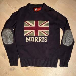 Säljer en snygg mörkblå tröja från Morris med Union Jack-flagga och texten 'Morris' på framsidan. Tröjan har grå armbågslappar och ribbade muddar. Perfekt för höst och vinter, både stilren och bekväm. Vid minsta fråga eller fundering hör av er🤝