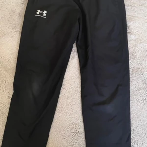 Under armour byxor  - Säljer ett par svarta träningsbyxor från Under Armour i bra skick. De är perfekta för träning och har en elastisk midja för extra komfort. Byxorna är gjorda i ett lätt och andningsbart material, vilket gör dem idealiska för intensiva träningspass.