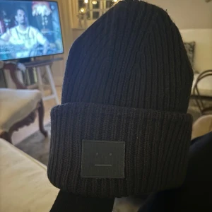 Acne Studios mössa - Säljer en snygg svart ribbad mössa från Acne Studios. Den är perfekt för kalla dagar och har en stilren design med en liten etikett framtill. Mössan är i mycket bra skick och passar de flesta tack vare sin flexibla passform!!!!