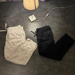 Beige och svarta linnebyxor Zara o Cubus - Två par linnebyxor i beige och svart. De har en avslappnad passform med resår i midjan och snörning för extra komfort. Perfekta för en chill dag hemma eller en snabb tur till affären. Materialet ser mjukt och bekvämt ut, idealiskt för vår o sommar!