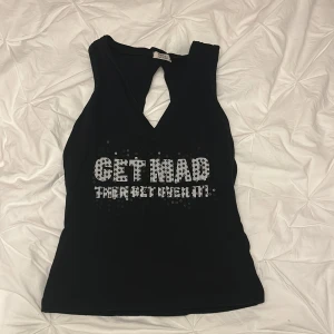 Svart ärmlös topp med text - Snygg svart ärmlös topp med texten 'GET MAD THEN GET OVER IT' i glittriga bokstäver. Toppen har en unik design med en liten öppning framtill. Perfekt för en utekväll! Från only och kan stylas snyggt y2k!