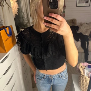 Svart blus från Zara - Säljer en snygg svart blus från Zara i storlek S. Den har korta ärmar och fina volangdetaljer framtill. Perfekt för både vardag och fest! 🖤aldrig använd, men utan prislapp 