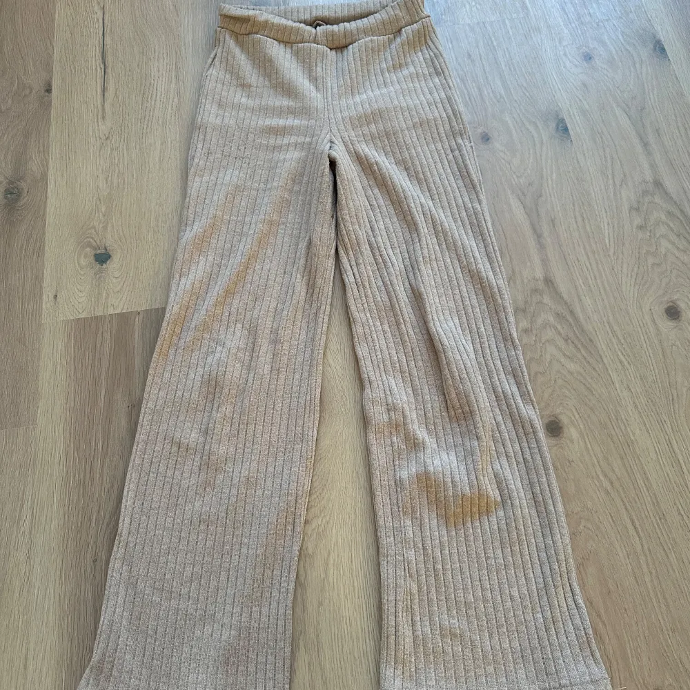 Säljer ett par beige ribbade byxor i loose fit. De är superbekväma och perfekta för en avslappnad stil. Byxorna har en hög midja och är gjorda i ett mjukt material som känns skönt mot huden. Perfekta för höst och vår!. Jeans & Byxor.