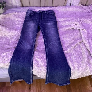 Mörkblå bootcut jeans - Säljer ett par snygga mörkblå bootcut jeans i bra skick. De har en cool tvättad look och broderade detaljer på bakfickorna. Perfekta för både vardag och fest! Passar till allt från sneakers till klackar.