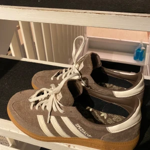 Adidas Spezial sneakers - Säljer ett par snygga Adidas Spezial sneakers i brunt mocka med vita detaljer och snörning. Skorna har en klassisk design med gummisula och är i mycket bra skick. Perfekta för både vardag och fest! 🤎🤎 använda bara några fåtal gånger så dom är som nya!