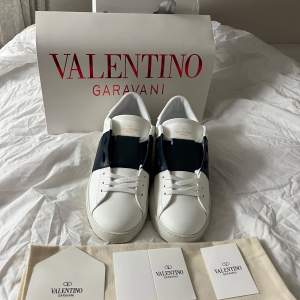 Säljer ett par snygga Valentino Garavani sneakers i vitt med mörkblå detalj över snörningen. Är st 44 men passar nog 43 om du har lite bredare fötter. Skolådan är lite bucklig på vissa ställen men inget fel på skorna!!  (obs inte orgi na l) Dustbag ingår även