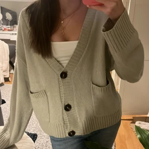 Kofta med fickor  - V ringad kofta. Mysig ljusgrön kofta med  knappar och två fickor fram. Superfin att ha över en t-shirt eller linne!