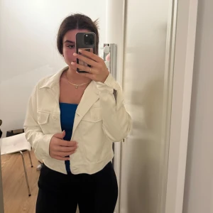 Vit croppad jacka från Zalando  - Säljer en snygg vit croppad jacka med knappar framtill. Perfekt för vår och sommar! Jackan har en stilren design med långa ärmar och två bröstfickor. Passar både till vardags och fest. 🕶️✨