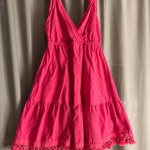Rosa sommarklänning med spetsdetaljer - Säljer en superfin rosa klänning perfekt för sommaren! Den har en v-ringad design och är ärmlös med vackra spetsdetaljer längst ner. Klänningen är i ett lätt och luftigt material, perfekt för varma dagar. Passar både till stranden och sommarfester. 💖säljer då den inte kommer till användning!