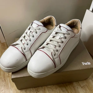 Vita sneakers med röd sula - Säljer ett par Christian Loboutins i skinn med coola röda detaljer och en ikonisk röd sula. Skorna har använts i 1 år men är fortfarande i bra skick. Perfekta för både vardag och fest! Allting medföljer såklart såsom dustbag/box och fler detaljer. Skorna har även godkänts av Kicksnstuff!. Säljer billigt eftersom att de är rätt använda Skorna kommer personligt rengöras innan köp. Möts upp!!