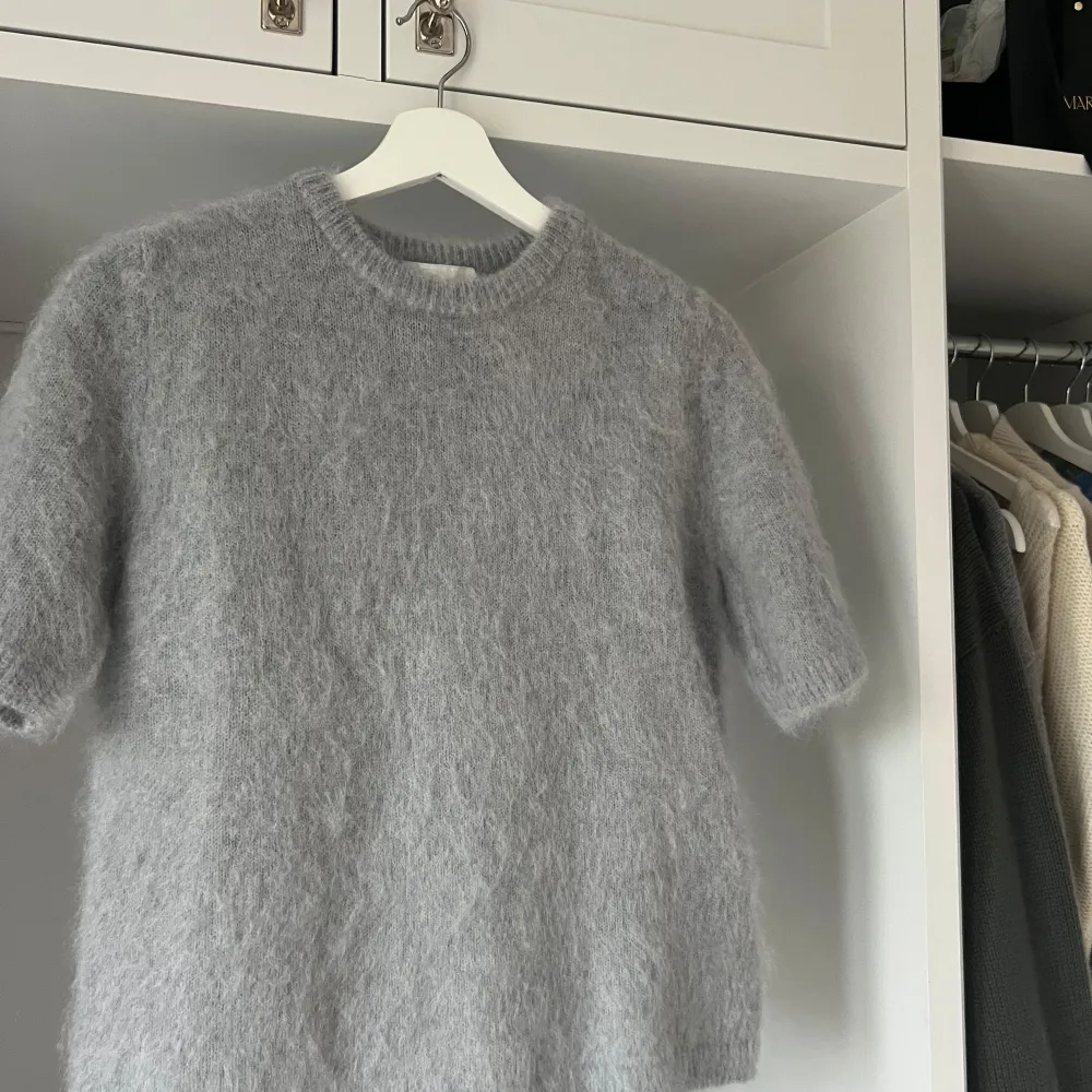 Säljer en supermjuk och fluffig grå stickad topp med korta ärmar. Perfekt både på sommaren med kjol/shorts eller vinter/höst med jeans. Tröjan har en normal passform som en t shirt. Helt oanvänd men inga lappar kvar. . Neuletakit & Villapaidat.