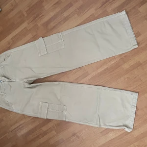 Beige low waist cargopants från Perfect Jeans - Säljer ett par snygga beige cargopants från Perfect Jeans. De har en loose passform med praktiska fickor på sidorna. Perfekta för en avslappnad stil och passar till de flesta tillfällen. Storlek 34.