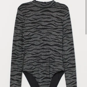 Svart och silver glittrig body - Säljer en supercool svart och silver glittrig body med långärmad design. Den har ett zebramönster och en djup öppen rygg som ger en extra wow-effekt. Perfekt för festliga tillfällen när du vill sticka ut! ✨