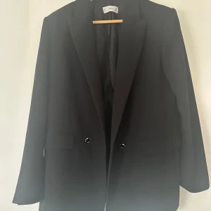 Kavaj i jättefint skick - En svart kavaj från Mango med gulddetaljer i jättefint skick. Är i storlek XL och är true to side, men går att använda som oversized om man är i storlek M/L. Nypris var 1299 säljer för 600kr 