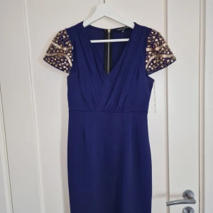 Marinblå Klänning med Glittriga Detaljer - Hej säljer min mammas klänningar. Detta är en väldigt fin klänning med glittriga detaljer. Den passar också till många tillfällen. Den är I storlek M  och har används bara ett fåtal gånger. Släpper för 349:-