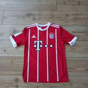 Fotbollströja Bayern München 16/17 - Säljer nu en jättefin fotbollströja från Bayern München i 2016/2017 säsongen. På ryggen är det den ikoniska Chilenska fotbollspelaren Vidal. Skick: 9/10 (lite cracking på framsidan) Storlek: Står XL men funkar perfekt som M.