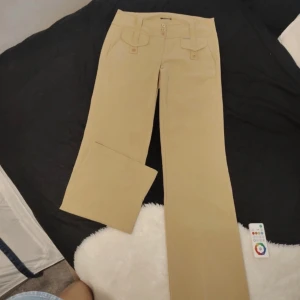 Lågmidjade kostymbyxor  - Kostymbyxor i beige färg. Storlek. På byxorna är 42 men midjemåttet är 42,5 och ytterbenslängden 105 så mera som en M☺️