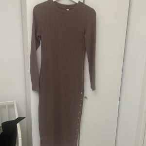 Brun ribbad klänning från Chiara Forthi - Säljer en snygg brun ribbad långklänning från Chiara Forthi. Den har långa ärmar och knappar längs sidan som ger en extra touch. Perfekt för höst och vinter, både till vardags och fest!