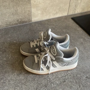 Adidas Campus, gråa/Vita - Gråa/vita Adidas campus i nästan ny skick. Storlek 38,5. De är väldigt svåra att få tag i och använda ca 5 gånger. Köpta för 1349 kr😊 Kontakta om ni har några frågor!! 