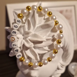 Armband med text "247365"  - Hemmagjort, helt nytt armband med pärlor i vitt och guld med texten "247365" inspiration av låten av Marcus och Martinus