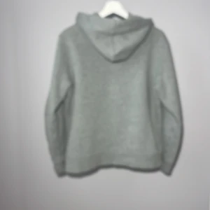 Grå hoodie från Polo Ralph Lauren - Säljer en stilren grå hoodie från Polo Ralph Lauren med dragkedja och fickor framtill. Perfekt för en avslappnad look. Den har en klassisk passform och är tillverkad i mjukt material för extra komfort.